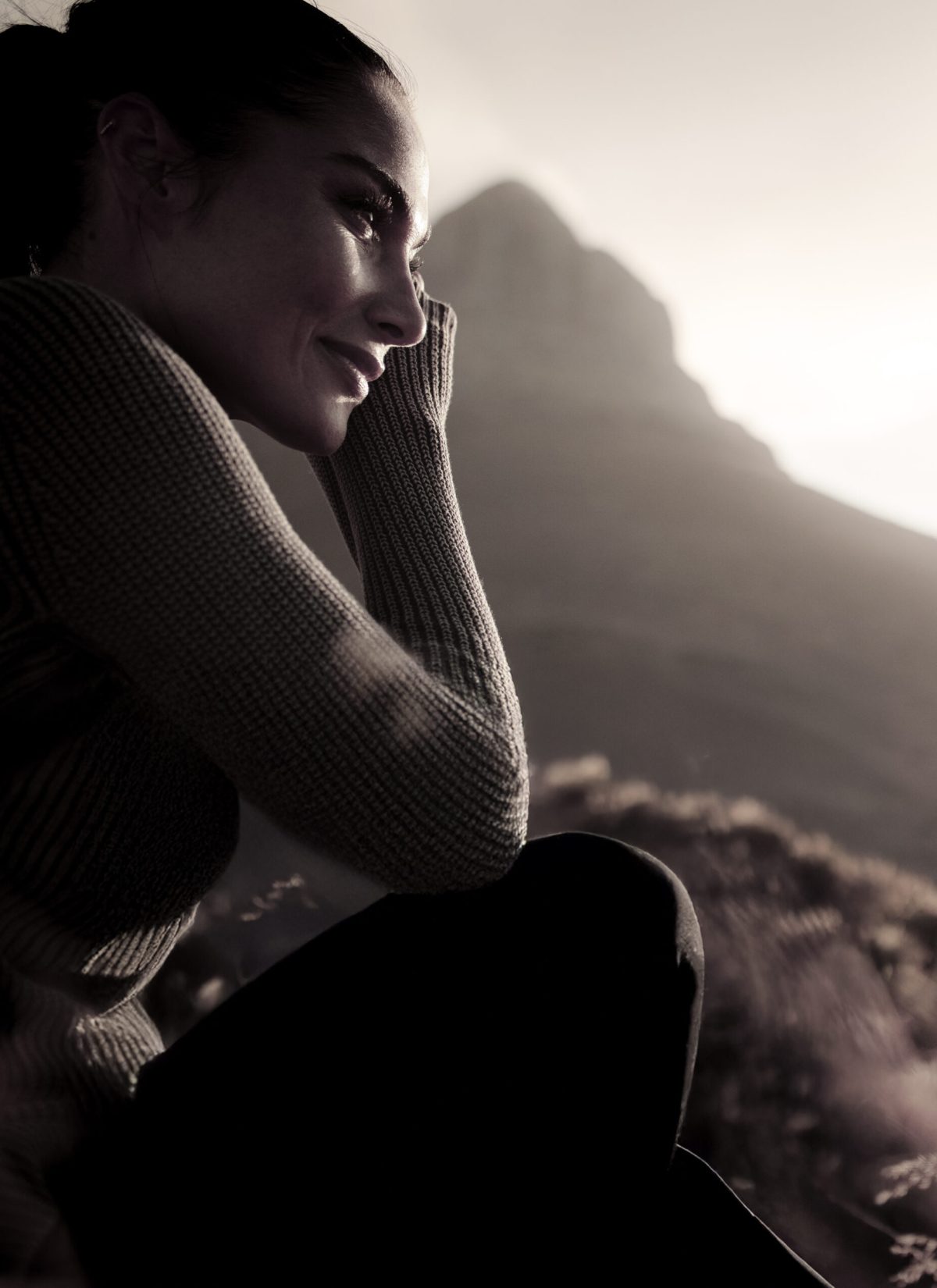 Woman sitting on meadow and looking away contemplating. Caucasian female tourist taking a rest after a country walk.